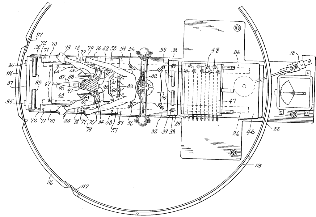 Top-down view of a machine with a circular frame and a bed inside. A person is strapped to the bed with legs splayed open.